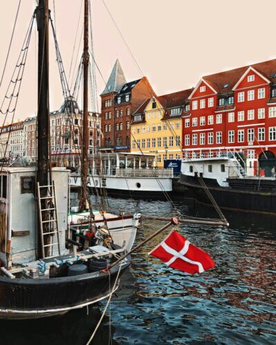 photo of the danish dannebrog flag flying on a black and white boat in the copenhagen harbour. photo by daria strategy on unsplash.